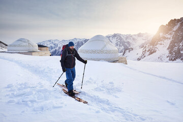 Fototapeta na wymiar Man skiing near yurt house snowy mountains