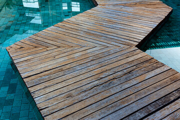 zigzag wooden bridge cross over the swimming pool.  japanese zig-zag walkway on water of pool.