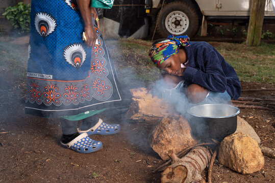 Older African Woman helping young teenage girls to  prepare a pot of tea