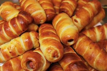 Sausage in dough or hotdog close-up. Lots of fresh pastries made of puff pastry and sausage. Top view. Background for bakery or fast food cafe.