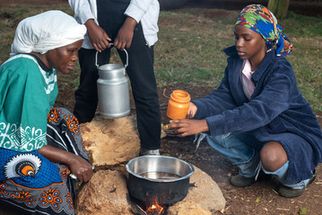 African Teenage girl stirring tea leaves into pot 