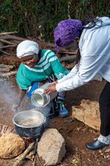 Young African teenager pouring fresh milk into pot 
