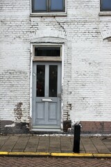 a gray door in an old crooked house facade