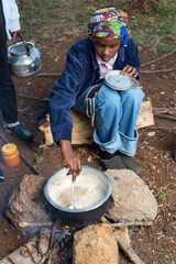 African Teenage girl stirring tea leaves into pot 