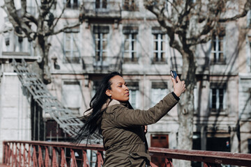 Fototapeta na wymiar young woman using her phone to take picture over bridge in city of Lyon France