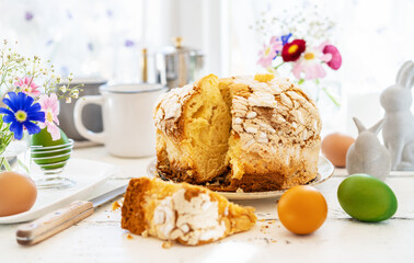 Easter concept with Italian easter cake Colomba, coloured eggs, spring flowers and rabbits