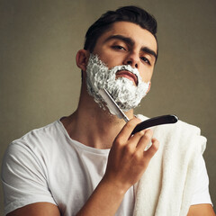 The mo needs to go. Cropped shot of a handsome young man shaving with a straight razor.