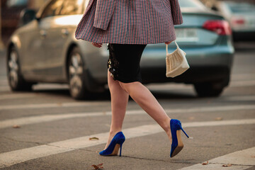 A woman in an oversized plaid jacket, black midi skirt and blue shoes in a European town. Stylish and confident business female walking down the street - obrazy, fototapety, plakaty