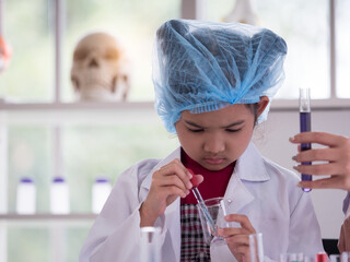 Cute little Asian girl wearing blue cap looking at the formula in the tube