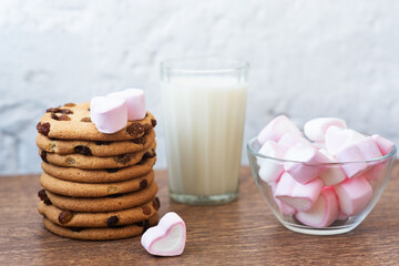 Fragrant, tasty, homemade cookies with raisins, marshmallows in the form of hearts and glass of fresh milk on the table