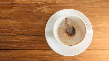 Top view of unwashed, dirty white coffee cup with saucers on wooden  table top, surface with copy space on the left.