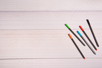 Mesa con fondo blanco con bolígrafos de colores.