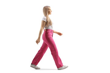 Full length profile shot of a young woman in pink jeans walking - obrazy, fototapety, plakaty