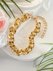 Fashion bijouterie - a large gold chain bracelet on a white stand