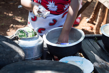 Young Teenage African Girl washing dishes at and outdoor area