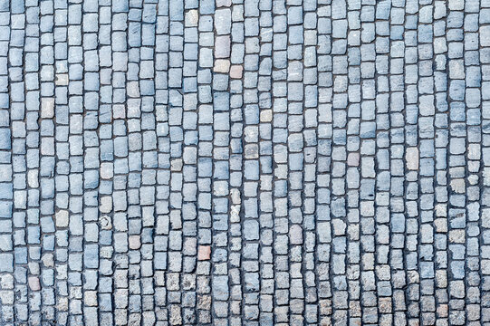 Cobblestone pavement texture background. Top view of stone road. Detail of granite sidewalk taken from above. Old street cobblestones for backdrop. Abstract vintage pavement with rough blocks.