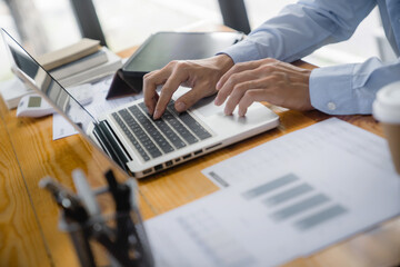 Close up of businessperson using laptop working with digital data.