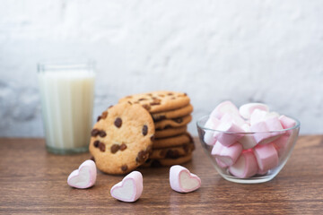 Fragrant, tasty, homemade cookies with raisins, marshmallows in the form of hearts and glass of fresh milk on the table