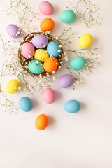 Top view layout of colorful painted Easter eggs with spring flowers on white background. Greeting card for Happy Easter. Copy space for your text. Vertical orientation.