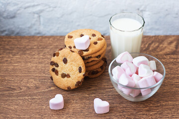 Fragrant, tasty, homemade cookies with raisins, marshmallows in the form of hearts and a glass of fresh milk on the table. Delicious, hearty, healthy breakfast. Copy space, high resolution