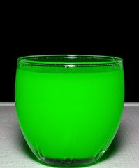 Photo of green water in the glass on black background