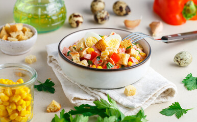 Delicious salad of bell peppers, corn, quail eggs, ham, bread croutons and parsley with olive oil. White plate, linen napkin. Selective focus