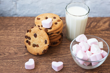 Fragrant, tasty, homemade cookies with raisins, marshmallows in the form of hearts and a glass of fresh milk on the table. Delicious, hearty, healthy breakfast. Copy space, high resolution
