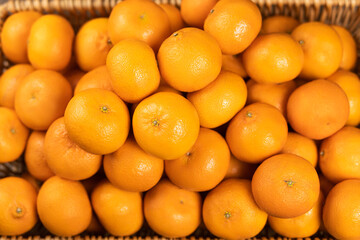 There are a lot of ripe tangerines in a wicker basket. Selective focus.