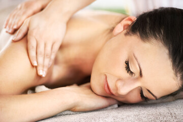 Fototapeta na wymiar Drifting away into a deep sleep. A beautiful young woman getting a massage from a spa therapist.