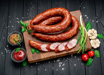 Appetizing smoked pork sausage on a dark background