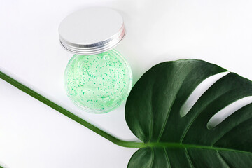 Herbal scrub and kiwi cosmetics on white background with green palm leave. Natural organic beauty products. Mockup