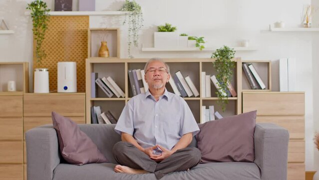 Mature Asian Man Doing Yoga For Meditation On Yoga Mat In Living Room At Home.Clam Of Senior Or Elderly Men Meditation Deep Breath And Relax At Cozy Home.Happy Retired Meditation At Home Concept