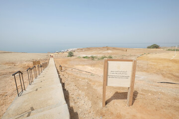 Signboard at the Dead Sea with stairs lead to the ocean seascape against sky