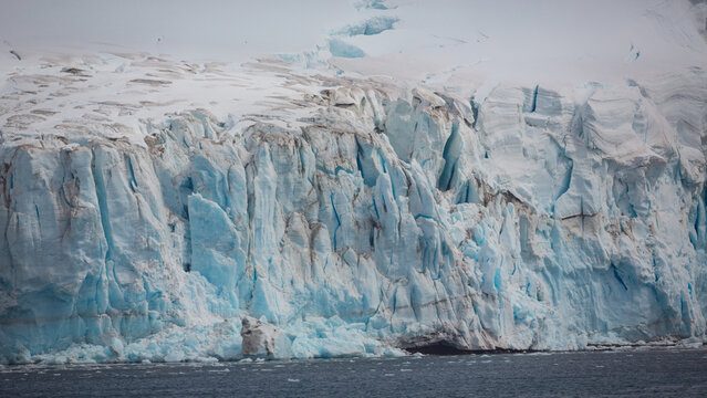 Eine zerklüftete weiß blaue Eiswand mit hohen Eiszacken eines riesigen Gletschers in der Antarktis