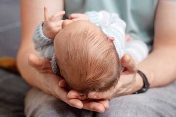 Father holding head of his newborn son in hands. The baby on hands at dad. Loving parents hand holding cute sleeping newborn baby child
