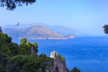 Capri Island. Magnificent view from the sea on the rocky shores of the island of Capri and the mountains surrounding the Amalfi coast in the background.