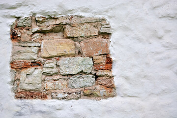 Fragment of old brickwork on the plastered white wall of the Church of George at the Market in the city of Veliky Novgorod.