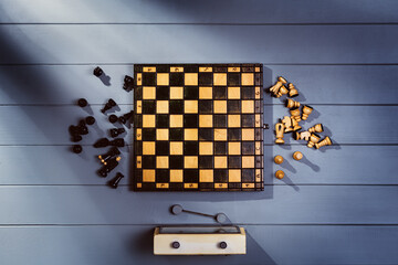 Top view on wooden chess board with figures during the game on gray wooden table background with copy space