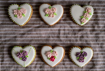 White gingerbread cookies with icing and flower decoration on a striped towel. Background for International Women's Day or Valentine's Day. High quality photo