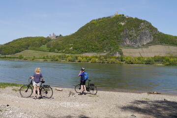 Radfahrer am Rhein mit Blick auf Siebengebirge und Schloss Drachenburg
