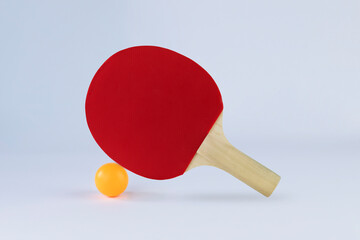 Red ping pong paddle and ball on light background. Active lifestyle concept