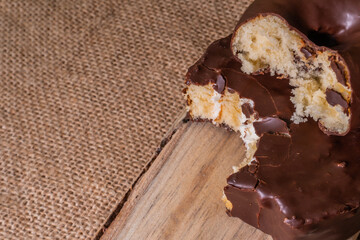 Wooden spoon with two pieces of industrial chocolate pastry with a bite on a hemp cloth and copyspace