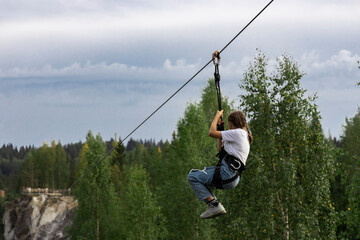 Girl gliding  in  road trolley zipline in the mountain park.