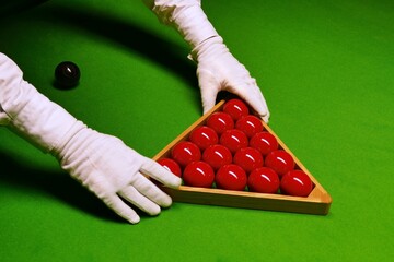 Snooker table and balls with referee arranging the balls