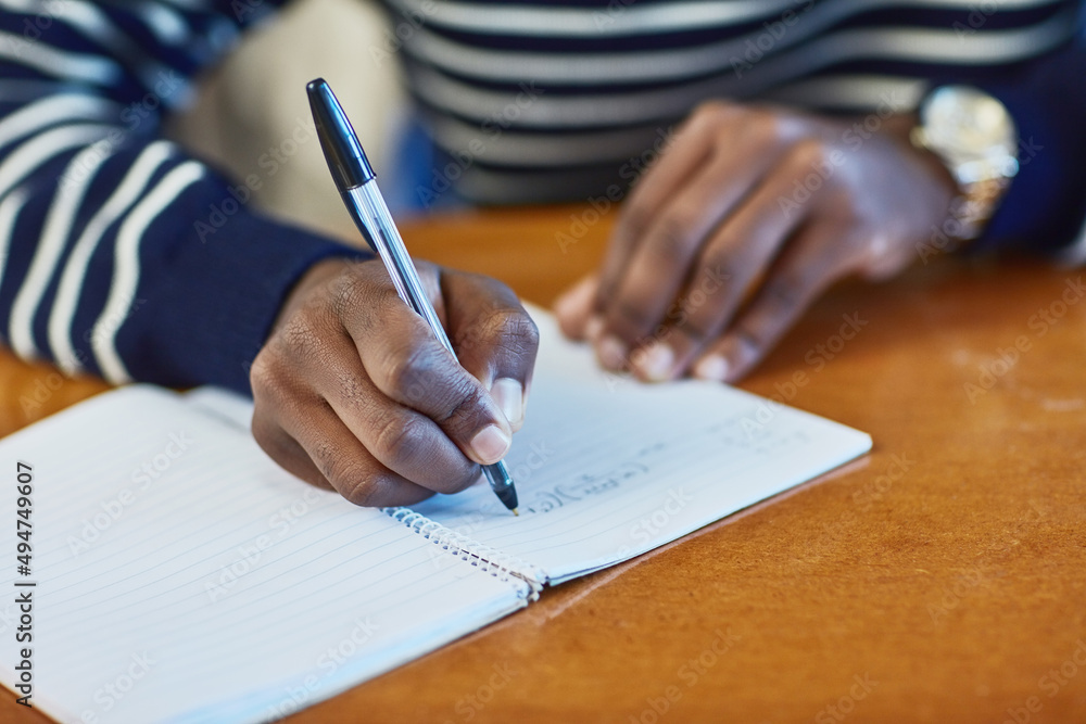 Poster Taking notes. Closeup shot of an unidentifiable university student writing in a book at campus.