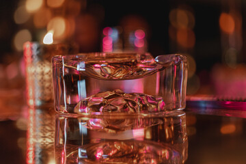 Empty glossy transparent ashtray with silky background bokeh