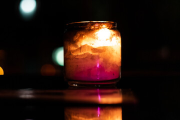 Glass candle with its reflection inside a dark room