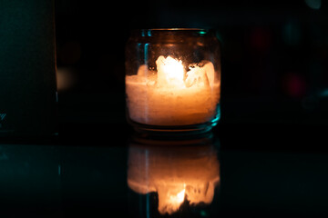 Glass candle with its reflection inside a dark room