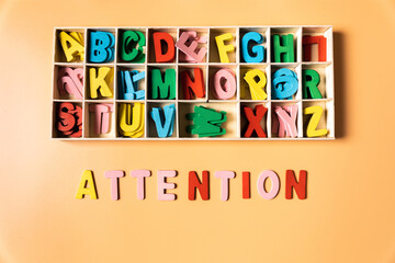 the word attention represented as a concept by wooden color letters, from the perspective of a child, over a background.