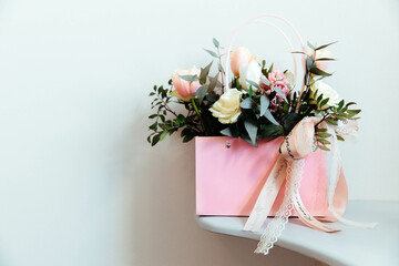 Bouquet of fresh flowers (roses, tulips, greens) in pink is located on plain light background. The concept of a holiday, wedding, engagement, valentine's day, women's day, birthday or other events. 